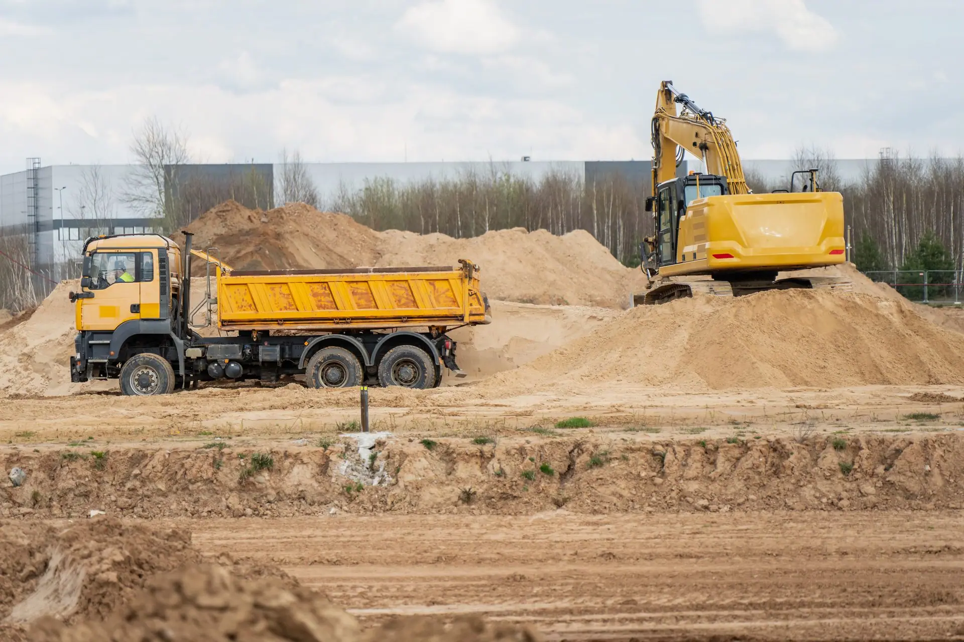 Excavator loading excavated soil into a tipper truck at an earthworks site