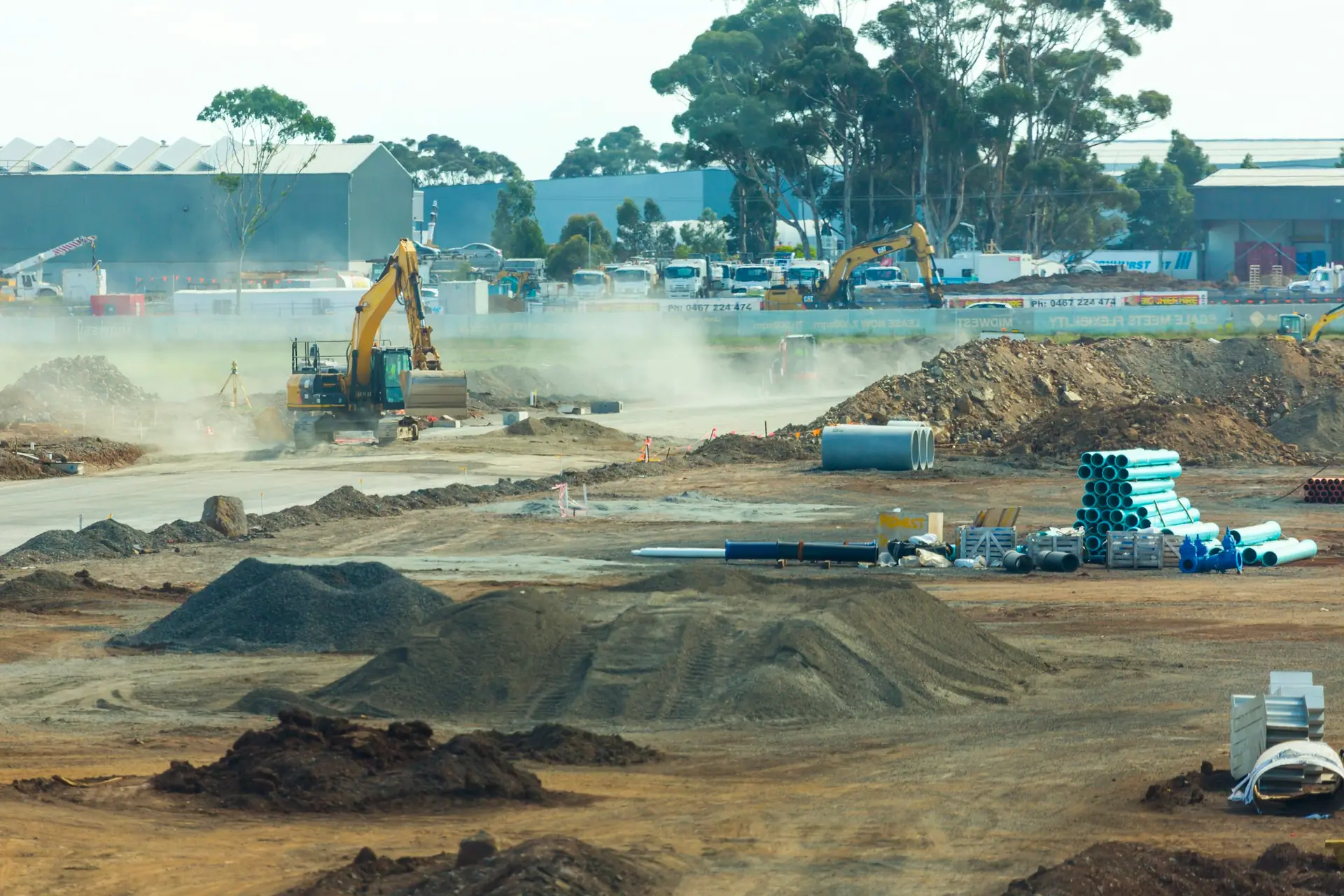Excavators working beside soil and gravel stockpiles on a construction site