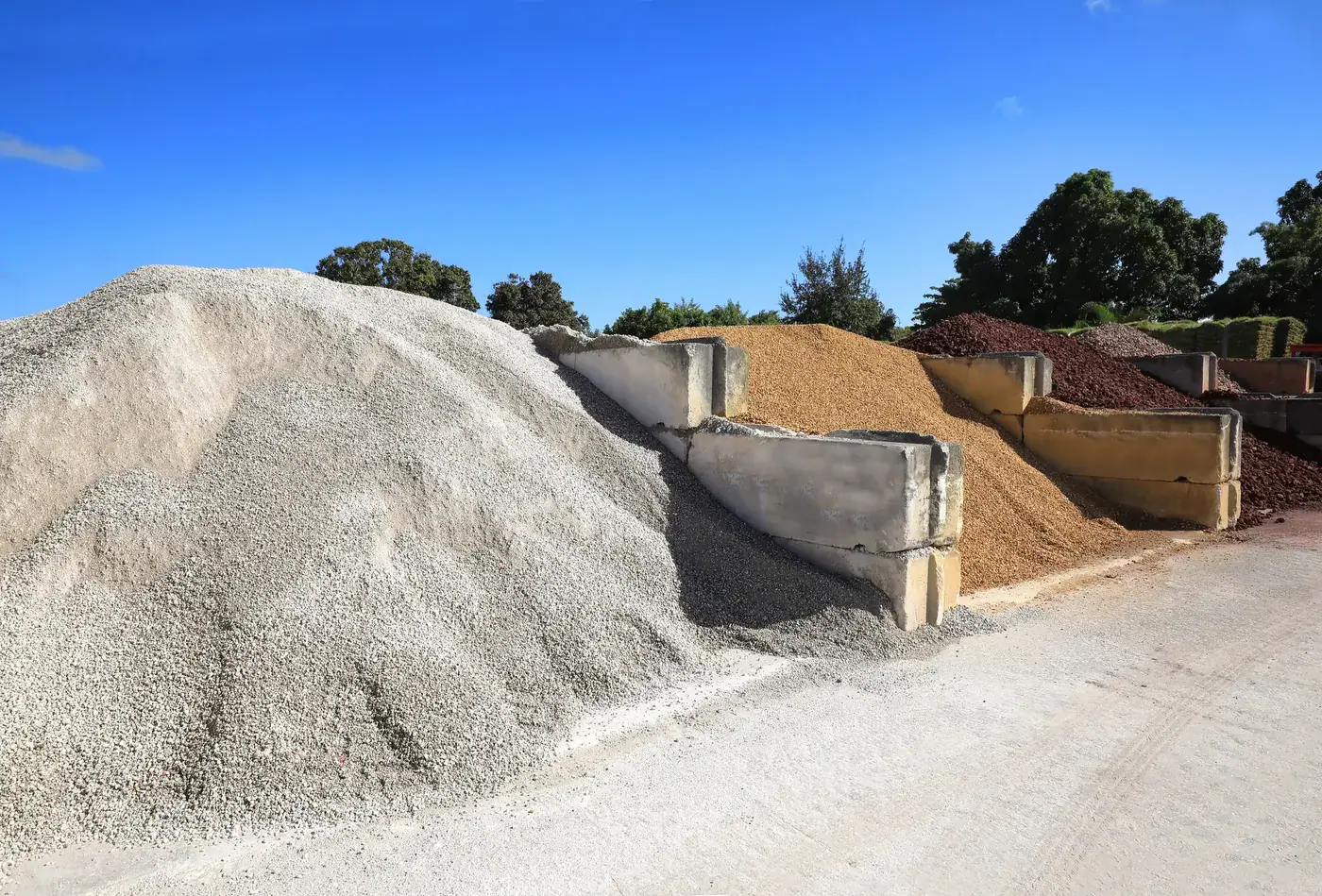 Stockpiles of graded aggregate, gravel and sand separated by concrete bays at a recycled materials yard